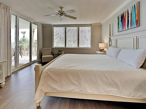 Un dormitorio con una cama grande con ventilador de techo. en Destin West Heron #306, en Fort Walton Beach