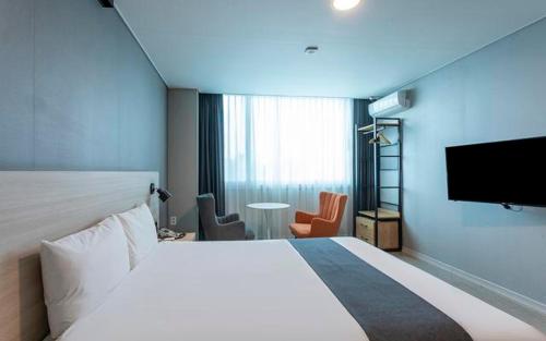a hotel room with a large bed and a flat screen tv at Gyeongpo Soo Hotel in Gangneung