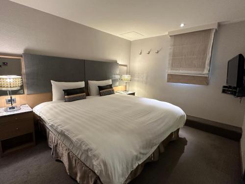 a bedroom with a large white bed and a window at 銀座飯店Ginza Hotel in Taipei