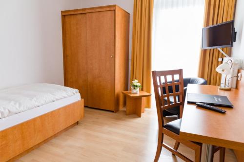 a bedroom with a bed and a desk with a computer at Gästehaus Wilgersdorf GmbH in Wilnsdorf