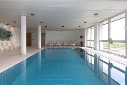 a swimming pool with a blue tile floor and windows at Gästehaus Wilgersdorf GmbH in Wilnsdorf