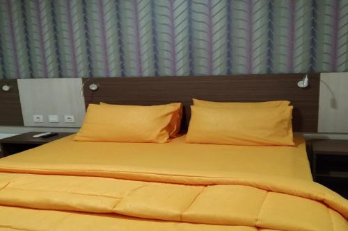a bed with yellow sheets and pillows in a bedroom at Smart Dream Aeropolis AR2 in Teko