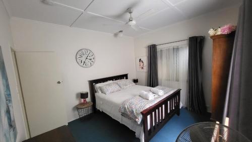 a bedroom with a bed and a clock on the wall at Nature's Melody Share Home in Brisbane
