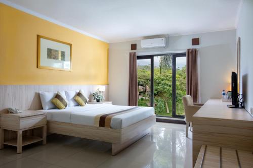 ein Schlafzimmer mit einem Bett und einem großen Fenster in der Unterkunft Palace Hotel in Puncak