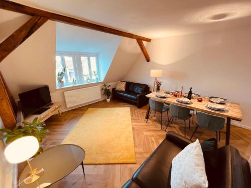 uma sala de estar com uma mesa e um sofá em Jugendstil-Altbauwohnung mit Dachterrasse direkt an der Karlsaue em Kassel