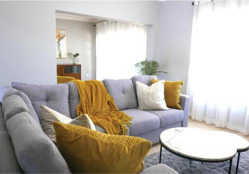 a living room with a blue couch with yellow pillows at Waterside Cottages & Villas - Self Catering in Gaborone