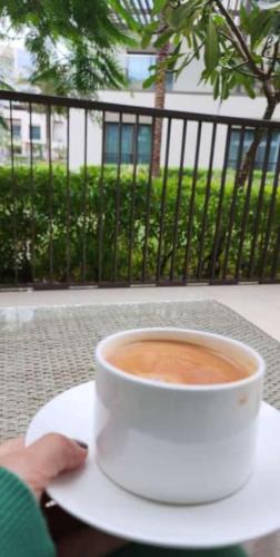 a person holding a cup of coffee on a table at Address Beach Resort Fujairah Apartment 2 Bed Rooms and Small Bed Room - Ground Floor 3011 in Al Aqah