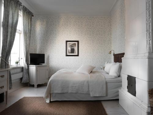 a white bedroom with a bed and a television at Grand Hotel Marstrand in Marstrand