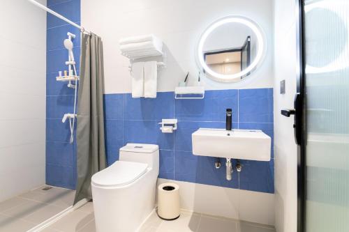 ein blau gefliestes Badezimmer mit Toilette und Waschbecken in der Unterkunft Puzzle Hotel Guangzhou Fenghuang New Village Subway Station in Guangzhou
