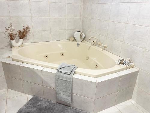 a white bath tub in a white tiled bathroom at The Scarborough Beach House - Walk to the beach! in Perth