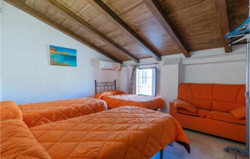 1 dormitorio con 2 camas y sofá naranja en Stunning Home In Cuevas De San Marcos With Outdoor Swimming Pool, en Cuevas de San Marcos