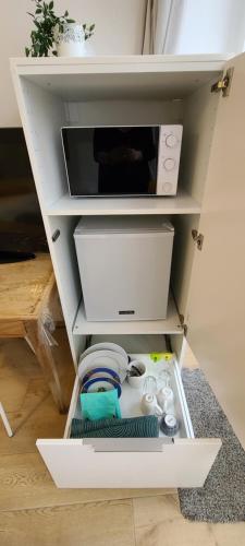 a white shelf with a microwave and dishes in it at Chambre de charme à Saulieu in Saulieu