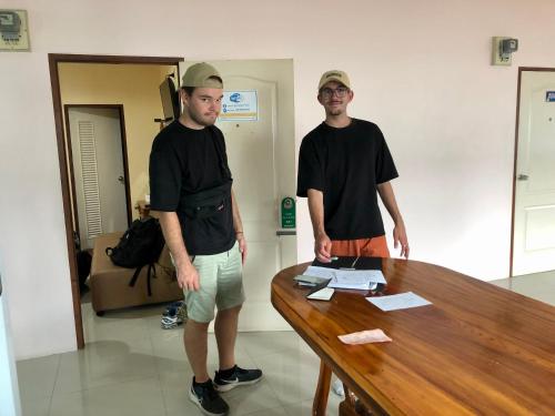 two men standing next to a wooden table at Baansrisuthum in Don Sak