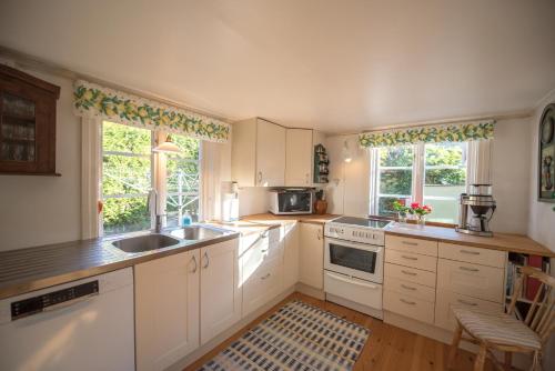 a kitchen with white cabinets and a sink at Huset Lövhyddan - SWEEDS Loftahammar in Loftahammar