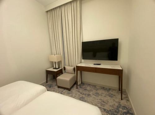 a hotel room with a bed and a desk with a television at Address Beach Resort Fujairah Apartment 2 Bed Rooms and Small Bed Room - Ground Floor 3011 in Al Aqah