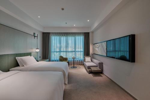 a hotel room with two beds and a flat screen tv at Empark Grand Hotel Kunming in Kunming