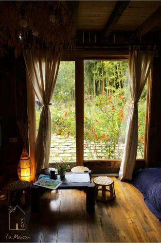 a room with a large window with a table and chairs at Sa Moc - La Maison House & Bungalow in Sa Pa