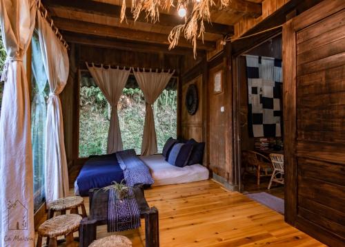 a bedroom with a bed in a room with wooden floors at Sa Moc - La Maison House & Bungalow in Sa Pa