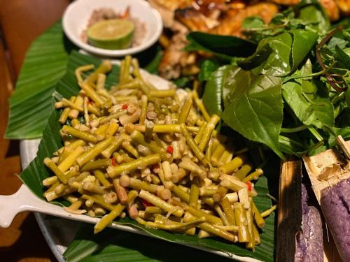 a plate of food with a salad and a spoon at Sa Moc - La Maison House & Bungalow in Sa Pa