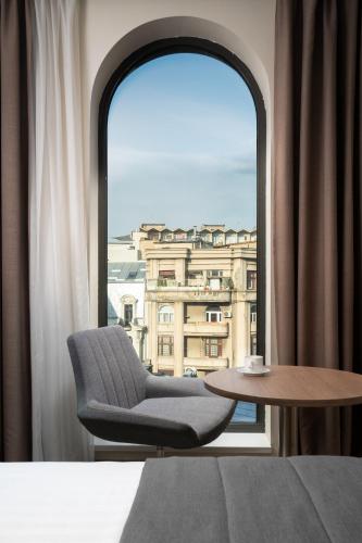 a room with a chair and a table and a window at Mercure Bucharest City Center in Bucharest