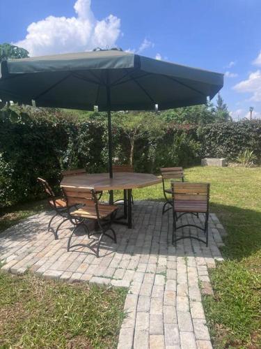a picnic table with an umbrella and two benches at Modern &homely guest suite w/free parking in Karen in Nairobi