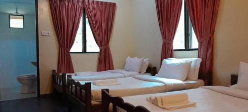 two beds in a room with red curtains at Kinabatangan Wildlife Lodge in Sandakan