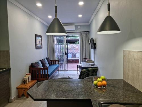 a kitchen and living room with a table with a bowl of fruit at Tarrentoela selfcatering guesthouse in Kathu