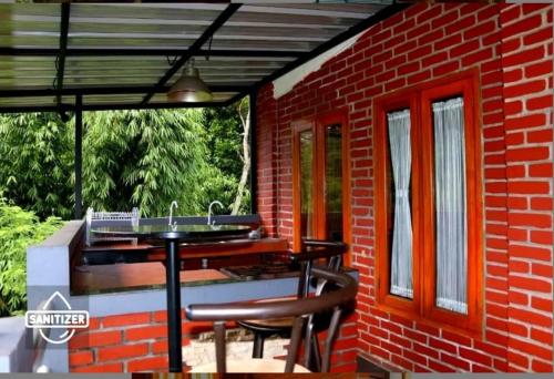 a patio with a table and chairs and a brick building at Bantal Guling Villa in Lembang