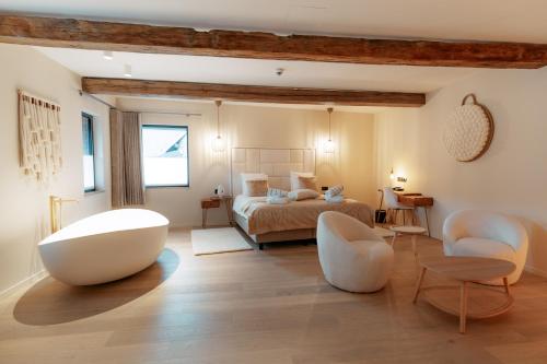 a bedroom with a bed and two white chairs at Domaine des Thermes in Awans
