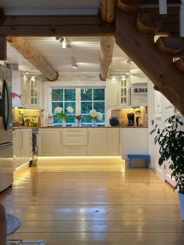a kitchen with white cabinets and a large window at Timber house with private beach and boat including. in Njurundabommen