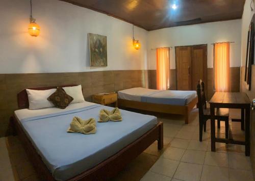 a bedroom with two beds and a desk with a piano at Dua Nina 2 Guesthouse in Gili Trawangan