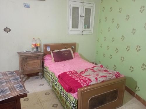 Large and cheerful home with 2 floors في الفيوم: غرفة نوم صغيرة مع سرير وبطانية وردية