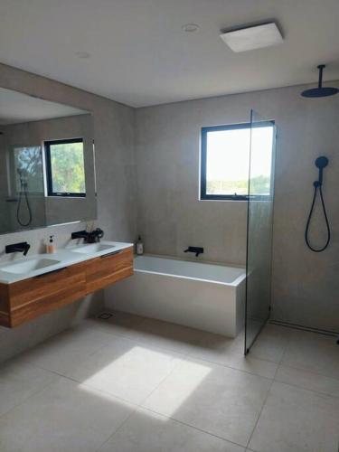 a bathroom with a tub and a sink and a shower at Golden Bay Beach House in Secret Harbour
