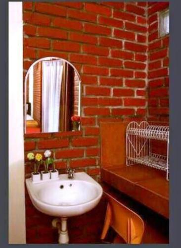 a bathroom with a white sink and a brick wall at Bantal Guling Villa in Lembang