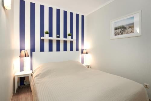 a bedroom with a white bed with blue and white stripes at Ostseeperle in Brasilien