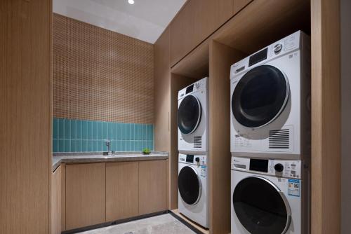 two washing machines in a kitchen with a sink at Home2 Suites By Hilton Foshan Jiujiang in Jiujiang