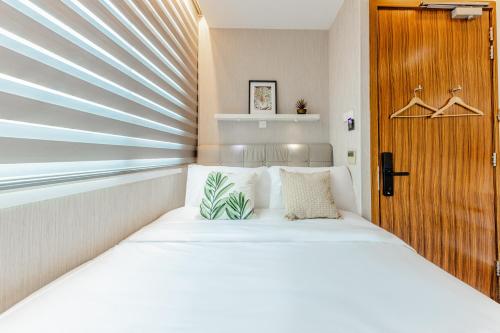 a small bedroom with a bed and a wooden door at D'Nova Hotel Bugis in Singapore