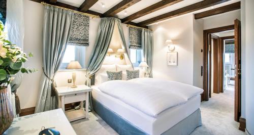a bedroom with a white bed and a table at Victor's Residenz-Hotel Schloss Berg in Nennig