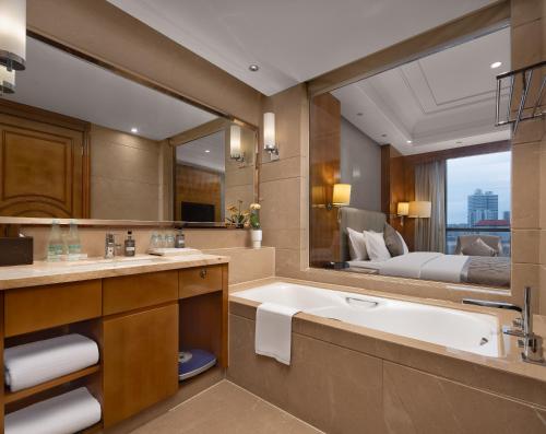 bagno con vasca e grande specchio di WorldHotel Grand Jiaxing Hunan a Changsha