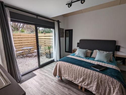 オーダンゲーヌにあるLa Rogeraie Cap gris nezのベッドルーム1室(ベッド1台付)、スライド式ガラスドアが備わります。
