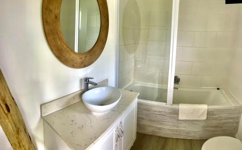 a bathroom with a sink and a tub and a mirror at Ocean View Hotel in Coffee Bay