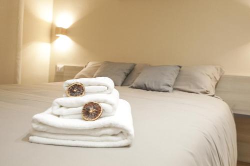 a bed with white towels and two watches on it at Etna Vibes Home in Catania
