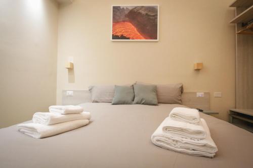 a bedroom with a bed with white towels on it at Etna Vibes Home in Catania