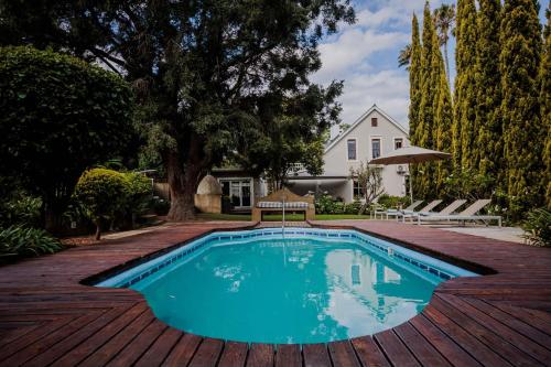a swimming pool on a wooden deck next to a house at De Oude Pastorie in Swellendam
