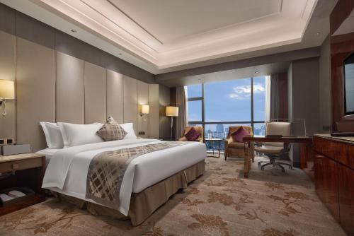 a bedroom with a large bed and a desk and a computer at WorldHotel Grand Jiaxing Hunan in Changsha