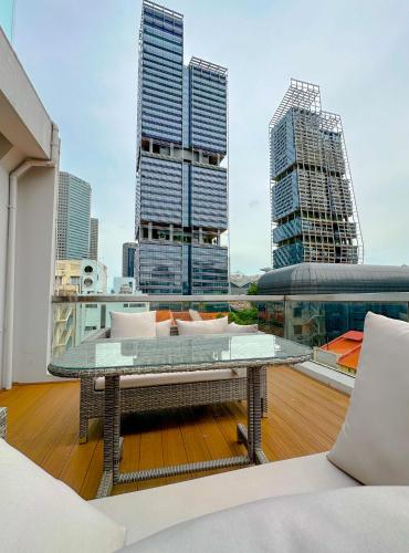 a glass table on top of a balcony with buildings at D'Nova Hotel Bugis in Singapore
