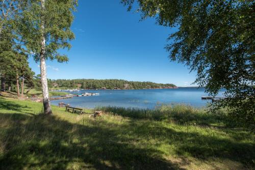 a park bench sitting in the grass next to a lake at Huset Lövhyddan - SWEEDS Loftahammar in Loftahammar