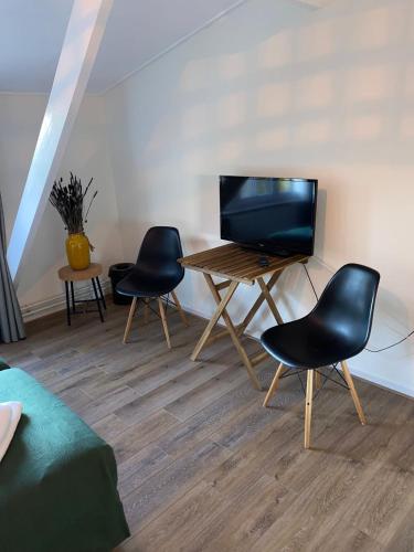 a living room with a table with chairs and a television at Herberg de Loohoeve in Schoonloo