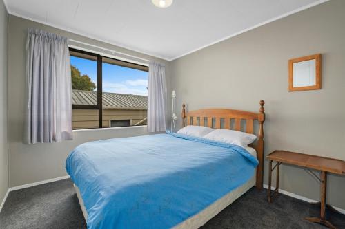 a bedroom with a blue bed and a window at Point Retreat - Lake Rotoiti Holiday Home in Rotoiti