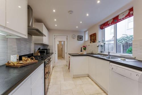 a large kitchen with white cabinets and a large window at 9 Morris Street in Sheringham